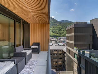 Experience breathtaking mountain views from this modern balcony, featuring comfortable outdoor seating and a stylish patterned rug.
