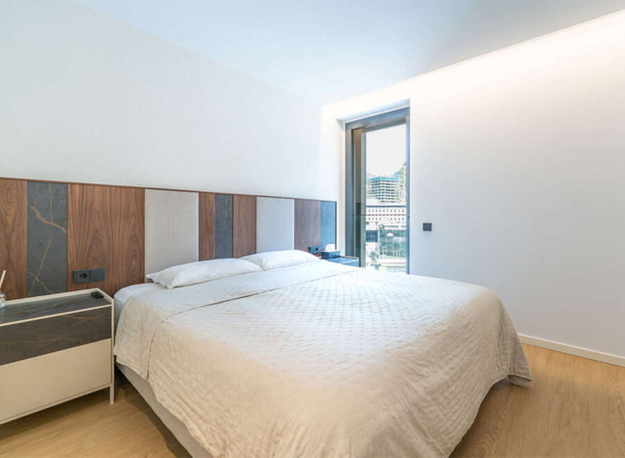 Experience modern comfort in this beautifully appointed bedroom, featuring a plush bed with a striking, multi-textured headboard.