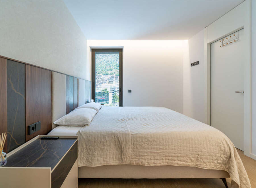 Experience modern comfort in this stylish bedroom, featuring a plush bed with a unique upholstered headboard and a convenient bedside table.