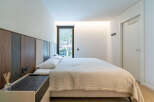 Experience modern comfort in this stylish bedroom, featuring a plush bed with a unique upholstered headboard and a convenient bedside table.