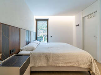 Experience modern comfort in this stylish bedroom, featuring a plush bed with a unique upholstered headboard and a convenient bedside table.