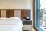 Experience modern comfort in this hotel room featuring a plush bed and a stylish headboard with wood and marble accents.