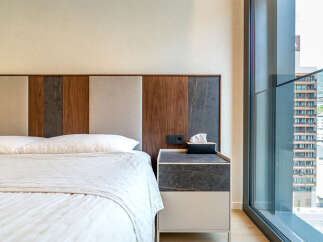 Experience modern comfort in this hotel room featuring a plush bed and a stylish headboard with wood and marble accents.