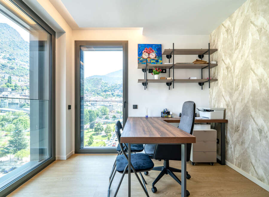 This modern home office features a spacious wooden desk with ergonomic chairs, perfect for productive work sessions.