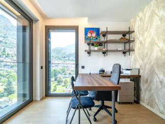 This modern home office features a spacious wooden desk with ergonomic chairs, perfect for productive work sessions.