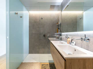 Experience modern luxury in this stunning bathroom featuring a spacious walk-in shower with a rainfall showerhead and sleek, minimalist design.