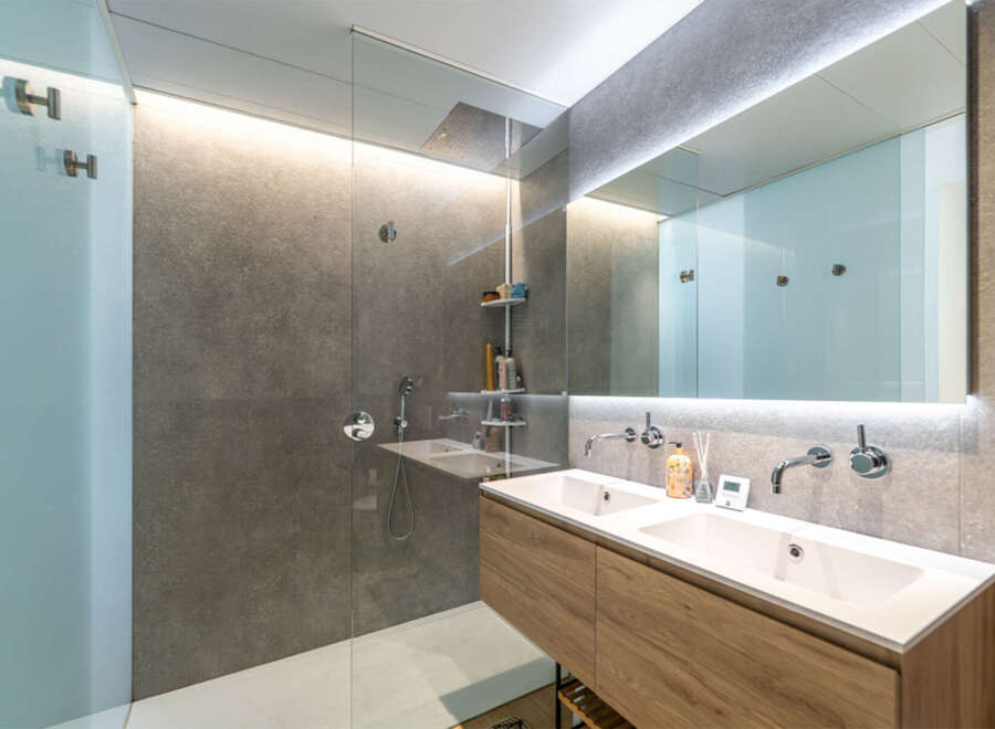 Experience modern luxury in this stunning bathroom featuring a spacious walk-in shower with a rainfall showerhead and a sleek double vanity with contemporary faucets.