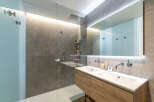 Experience modern luxury in this stunning bathroom featuring a spacious walk-in shower with a rainfall showerhead and a sleek double vanity with contemporary faucets.