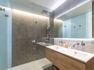 Experience modern luxury in this stunning bathroom featuring a spacious walk-in shower with a rainfall showerhead and a sleek double vanity with contemporary faucets.