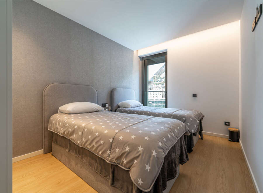 This modern bedroom features two comfortable twin beds, each adorned with a charming star-patterned duvet and plush grey throws.