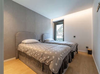 This modern bedroom features two comfortable twin beds, each adorned with a charming star-patterned duvet and plush grey throws.