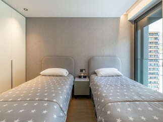 Discover this modern bedroom featuring two comfortable twin beds, each adorned with a charming star-patterned duvet and a plush white pillow.