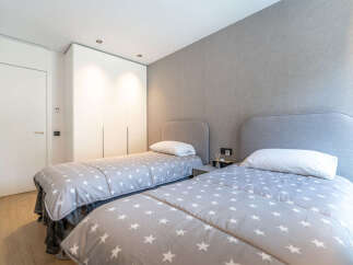 This modern bedroom features two twin beds with playful star-patterned comforters, perfect for a child's room or guest suite.