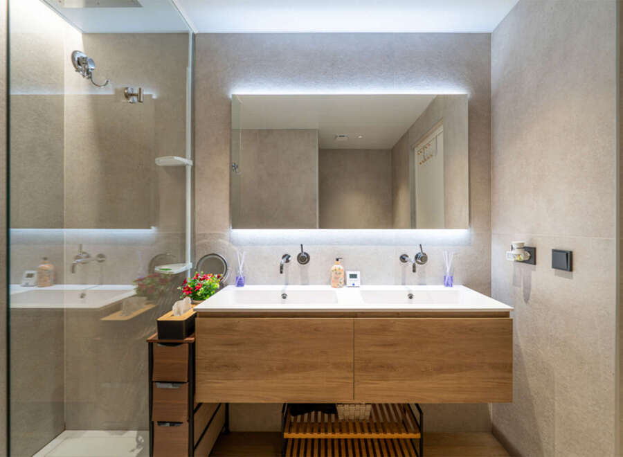 Experience modern luxury in this stunning bathroom featuring a sleek double vanity with a warm wood finish and integrated sinks.