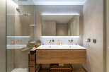 Experience modern luxury in this stunning bathroom featuring a sleek double vanity with a warm wood finish and integrated sinks.