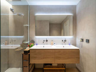 Experience modern luxury in this stunning bathroom featuring a sleek double vanity with a warm wood finish and integrated sinks.