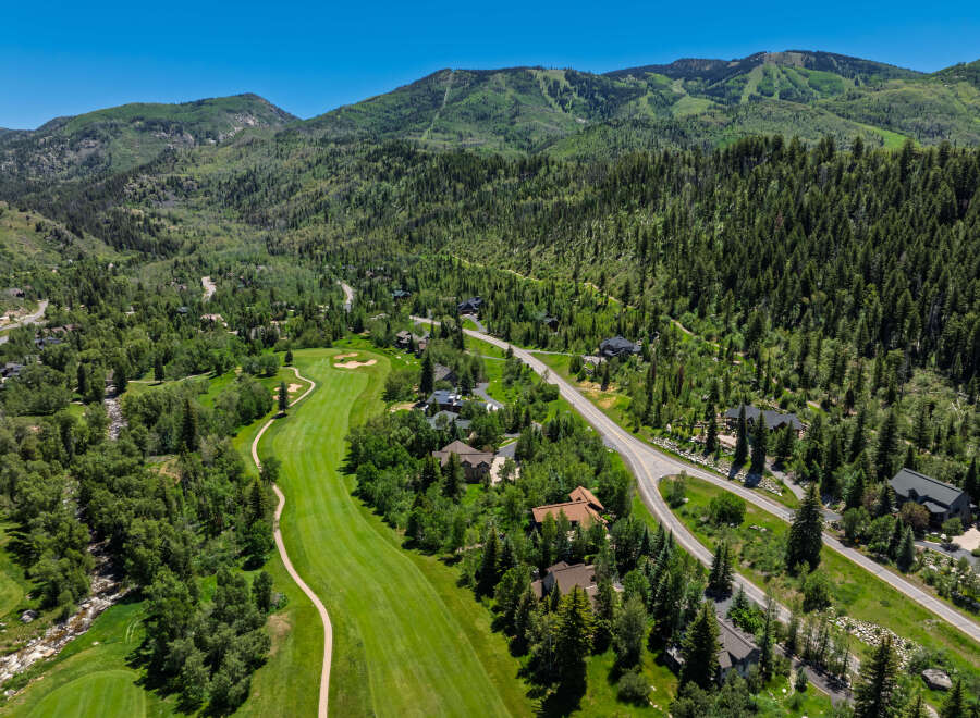 Experience luxury mountain living with this stunning aerial view of a golf course community nestled amidst lush green forests and rolling hills.