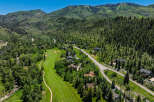 Experience luxury mountain living with this stunning aerial view of a golf course community nestled amidst lush green forests and rolling hills.