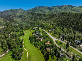 Experience luxury mountain living with this stunning aerial view of a golf course community nestled amidst lush green forests and rolling hills.