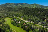 Experience luxury mountain living with this stunning aerial view of a sprawling estate nestled amidst lush greenery and majestic peaks.