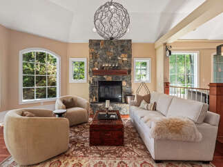 Experience luxurious living in this stunning living room, featuring a grand stone fireplace as the centerpiece.