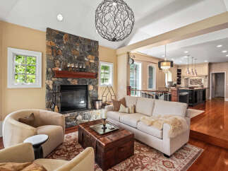Experience luxury living in this stunning home featuring a grand stone fireplace and an open-concept layout connecting to a gourmet kitchen.