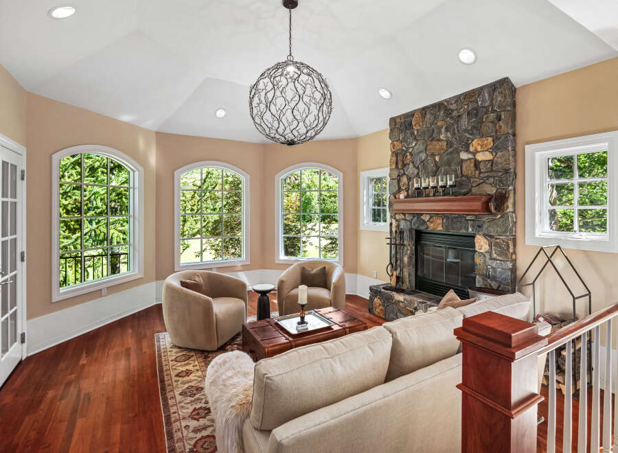 Experience luxurious living in this stunning living room, featuring a grand stone fireplace and a unique, artistic chandelier.