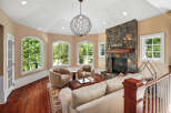 Experience luxurious living in this stunning living room, featuring a grand stone fireplace and a unique, artistic chandelier.