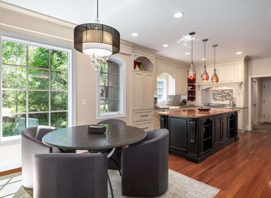 Experience luxury in this stunning kitchen, featuring a large granite island perfect for entertaining and a charming breakfast nook with a round table and plush seating.