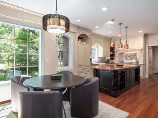 Experience luxury in this stunning kitchen, featuring a large granite island perfect for entertaining and a charming breakfast nook with a round table and plush seating.
