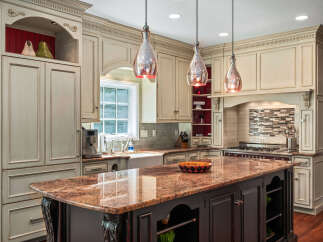 Experience luxury in this stunning kitchen, featuring custom cream cabinetry with intricate detailing and a grand granite-topped island perfect for entertaining.
