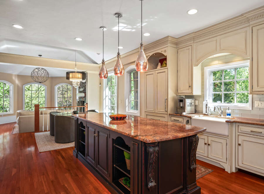 This spacious kitchen boasts a large granite-topped island with intricate dark wood cabinetry, perfect for meal preparation and casual dining.