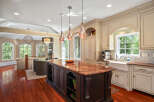 This spacious kitchen boasts a large granite-topped island with intricate dark wood cabinetry, perfect for meal preparation and casual dining.