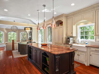 This spacious kitchen boasts a large granite-topped island with intricate dark wood cabinetry, perfect for meal preparation and casual dining.