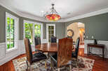 This elegant dining room features a round wooden table with upholstered chairs, perfect for intimate gatherings.