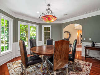 This elegant dining room features a round wooden table with upholstered chairs, perfect for intimate gatherings.