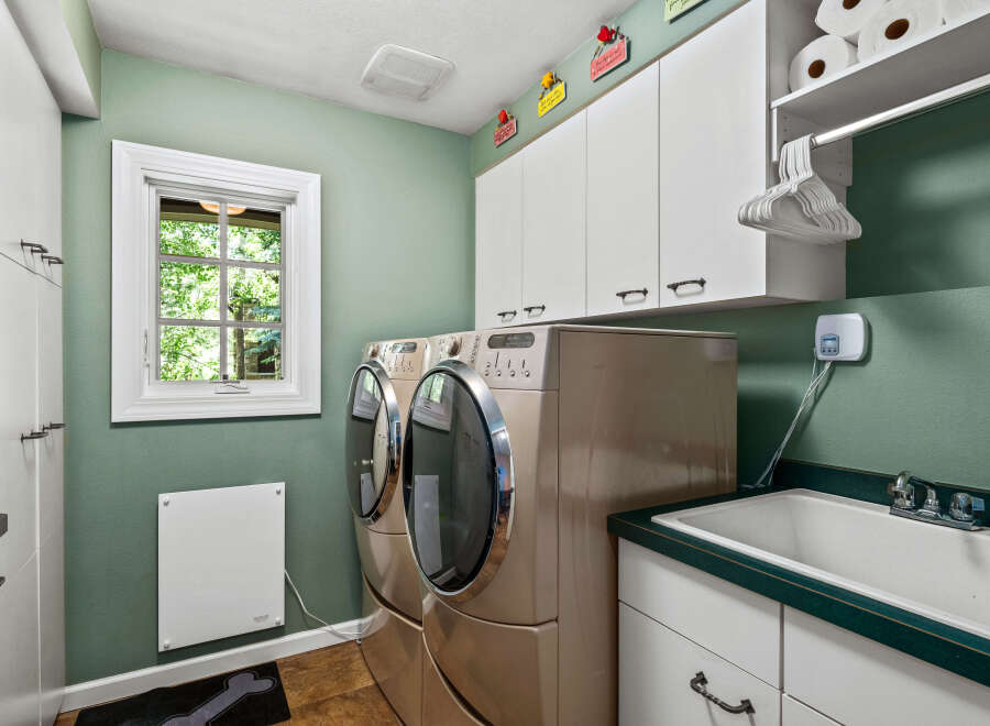 This spacious laundry room features a large sink and side-by-side washer and dryer units, perfect for handling large loads.