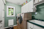 This spacious laundry room features a large sink and side-by-side washer and dryer units, perfect for handling large loads.
