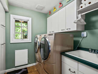 This spacious laundry room features a large sink and side-by-side washer and dryer units, perfect for handling large loads.