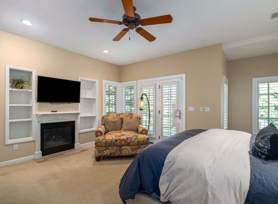 Experience ultimate comfort in this beautifully appointed bedroom, featuring a cozy fireplace and a large flat-screen TV for entertainment.