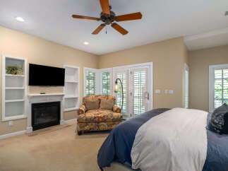 Experience ultimate comfort in this beautifully appointed bedroom, featuring a cozy fireplace and a large flat-screen TV for entertainment.