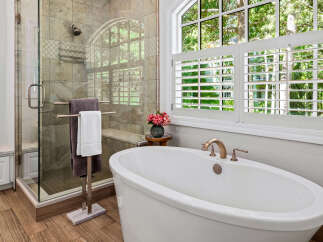 Indulge in luxury with this stunning bathroom featuring a freestanding soaking tub and a spacious glass-enclosed shower.