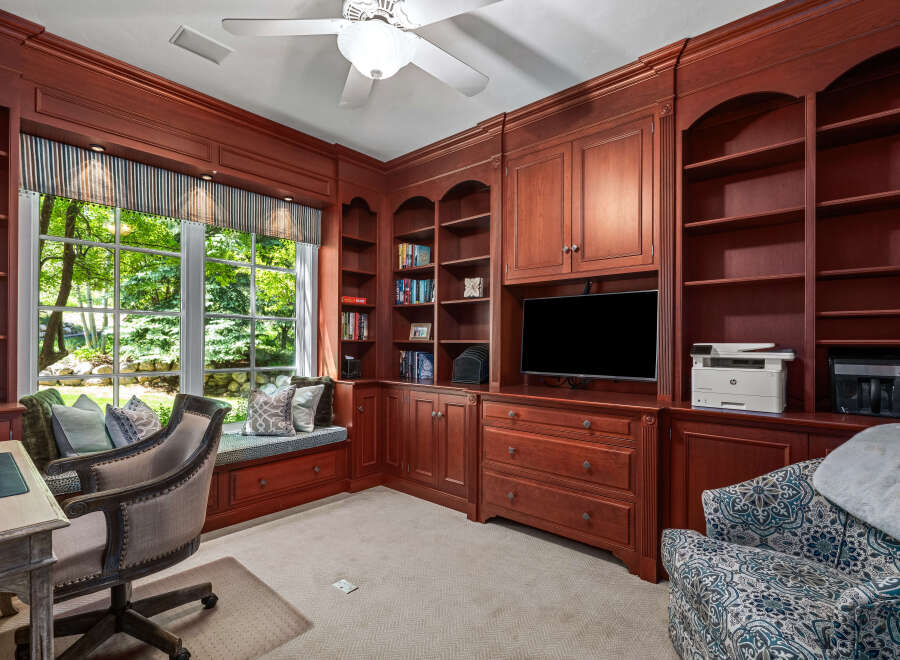 This home office features custom cherry wood built-in bookshelves and cabinetry, providing ample storage and a sophisticated aesthetic.