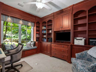 This home office features custom cherry wood built-in bookshelves and cabinetry, providing ample storage and a sophisticated aesthetic.