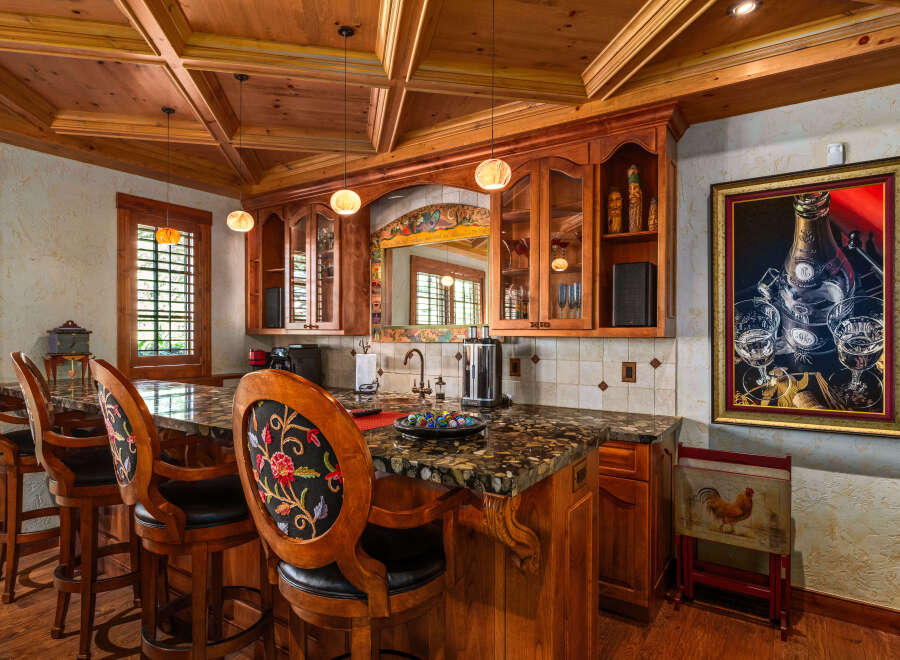 Step into this elegant home bar, featuring a stunning granite countertop and rich wooden cabinetry.