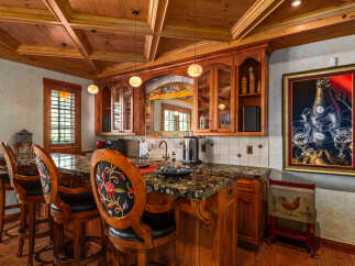 Step into this elegant home bar, featuring a stunning granite countertop and rich wooden cabinetry.