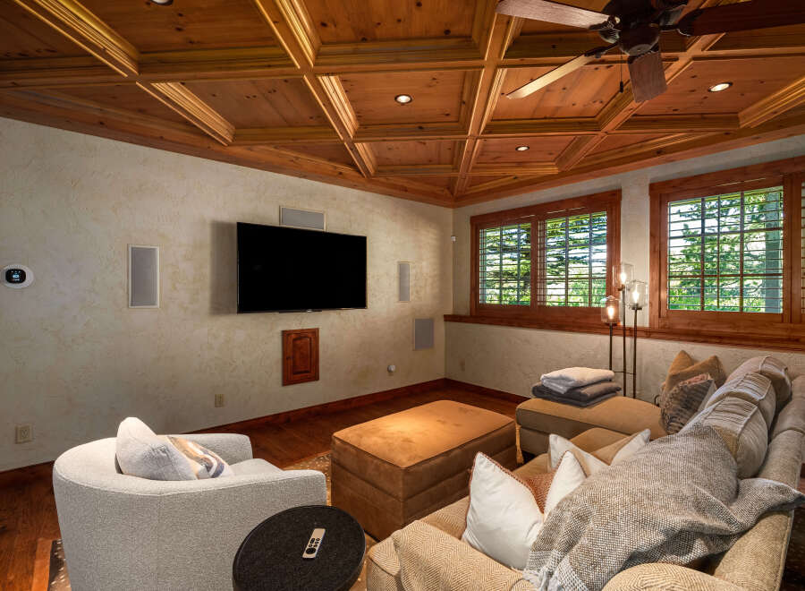 Experience ultimate relaxation in this cozy media room, featuring a large sectional sofa, plush armchair, and a convenient ottoman.