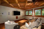 Experience ultimate relaxation in this cozy media room, featuring a large sectional sofa, plush armchair, and a convenient ottoman.