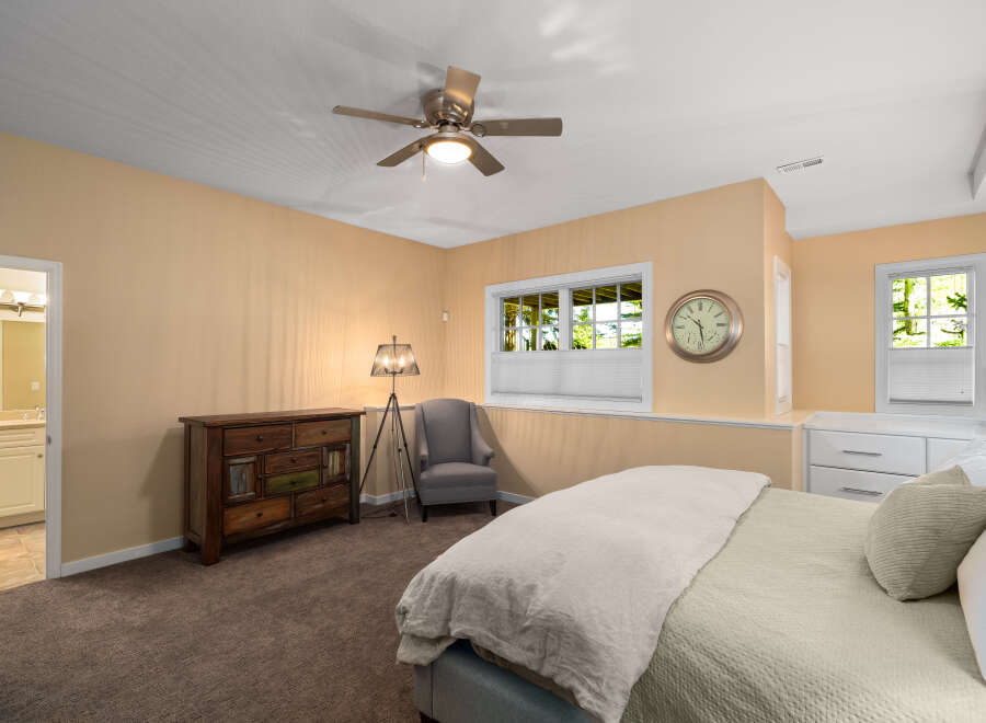 This charming bedroom features a comfortable bed with plush bedding, complemented by a stylish dresser and a cozy armchair.