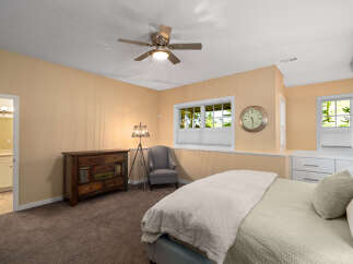 This charming bedroom features a comfortable bed with plush bedding, complemented by a stylish dresser and a cozy armchair.